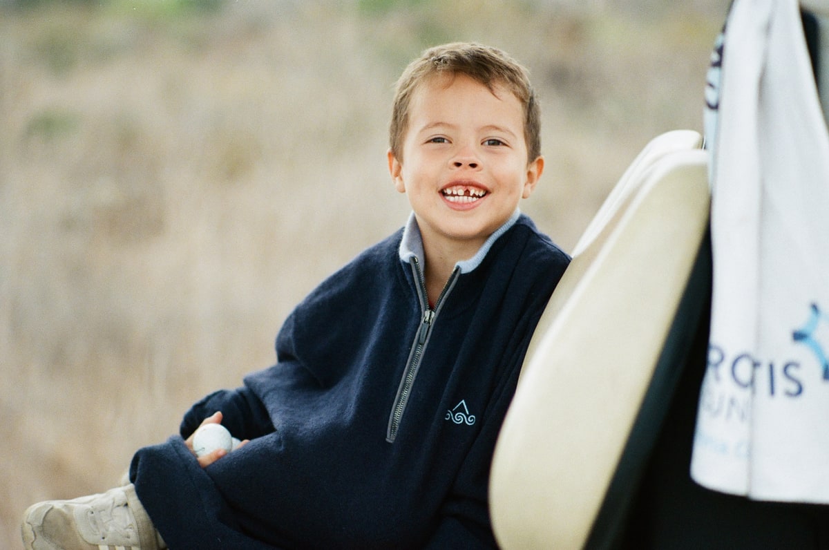 Baker smiles from the golf cart with a golf ball in his hand.