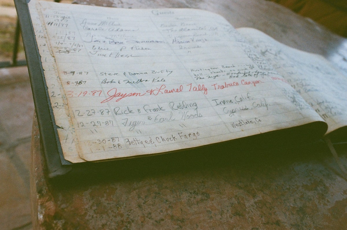 An open house guest book with a handwritten entry reading Tiger & Earl Woods.