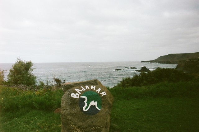 A rock painted with the Bajamar name and logo stands above the rocky coastline.