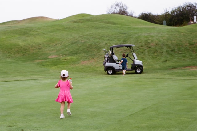 Baker heads toward the golf cart while Romee follows across the green.