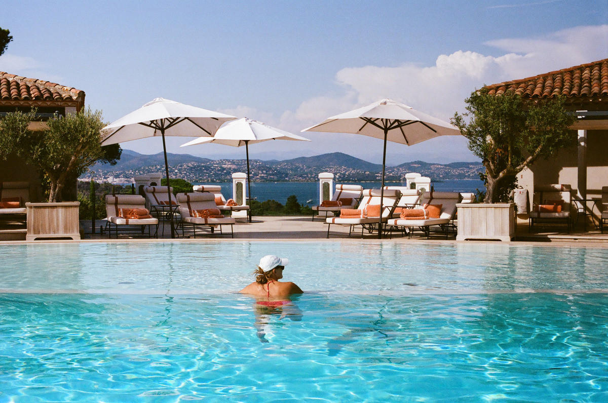 A person in a swimming pool, with umbrellas and the coast beyond