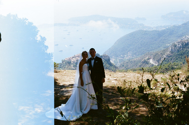 A couple in wedding clothes above the coast, with a light leak along the left edge