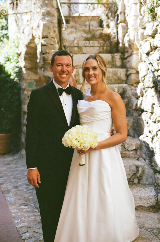 A couple in wedding clothes standing together in a stone passage