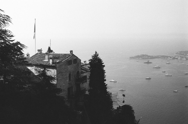 A black-and-white photograph of a stone building overlooking the coast